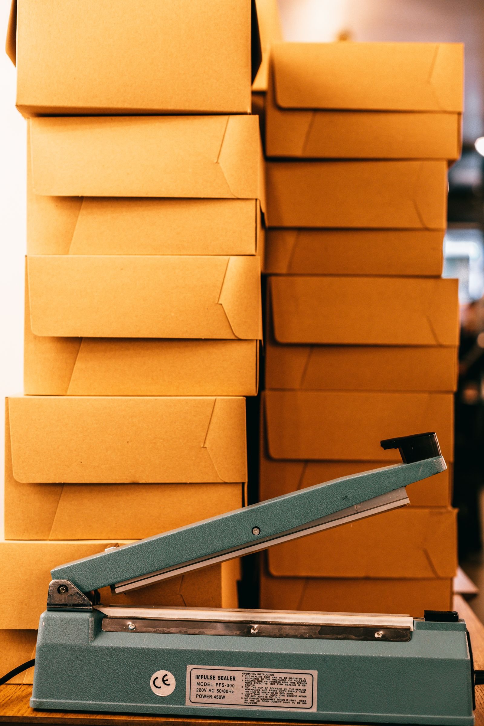 Impulse bag sealer on a packing table with stacks of cardboard shipping boxes