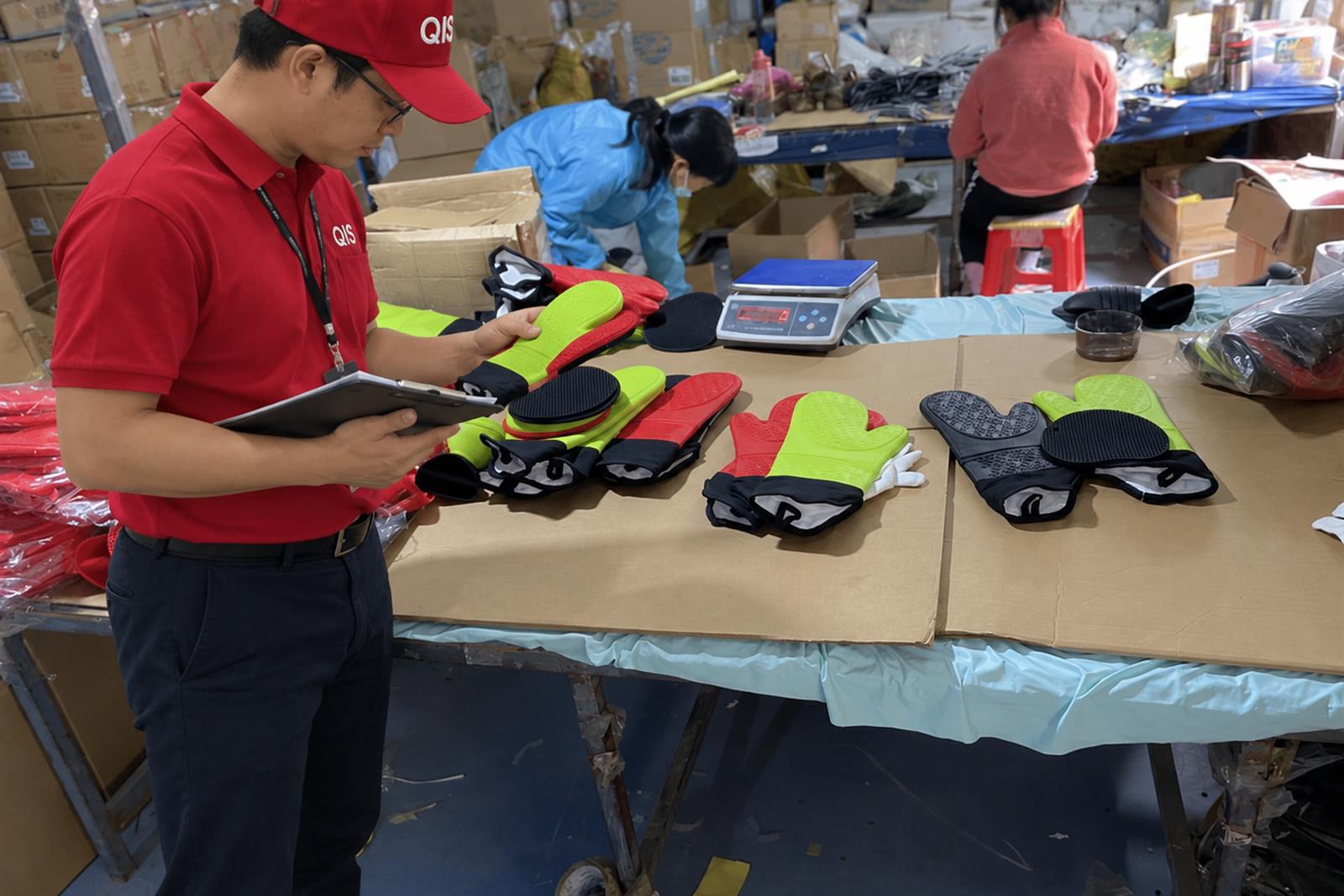 QIS inspector in red uniform checking products at a factory inspection table